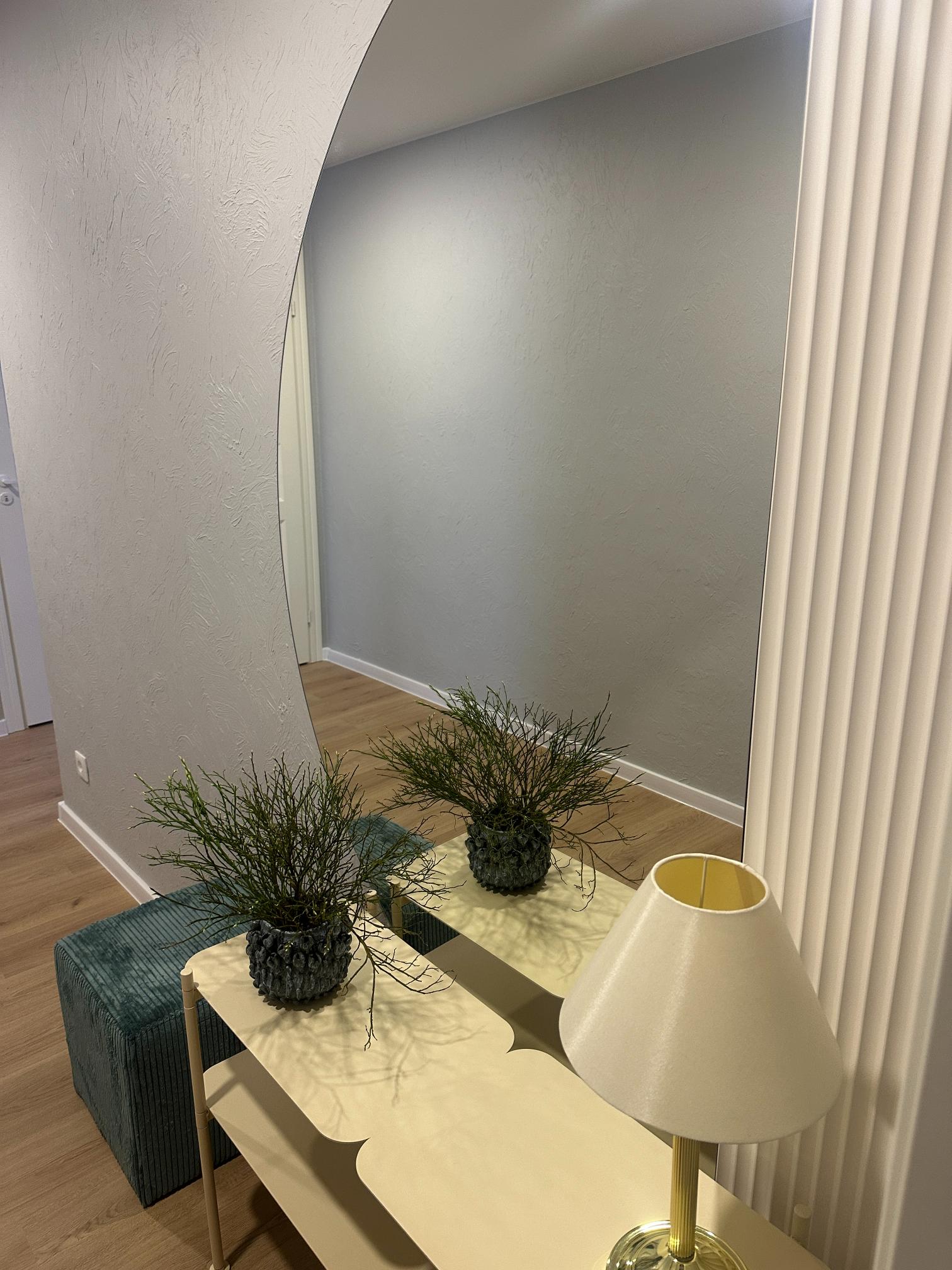 Minimalistlik esik modernse peegli, dekoratiivsete taimede ja helekollase konsoollauaga.