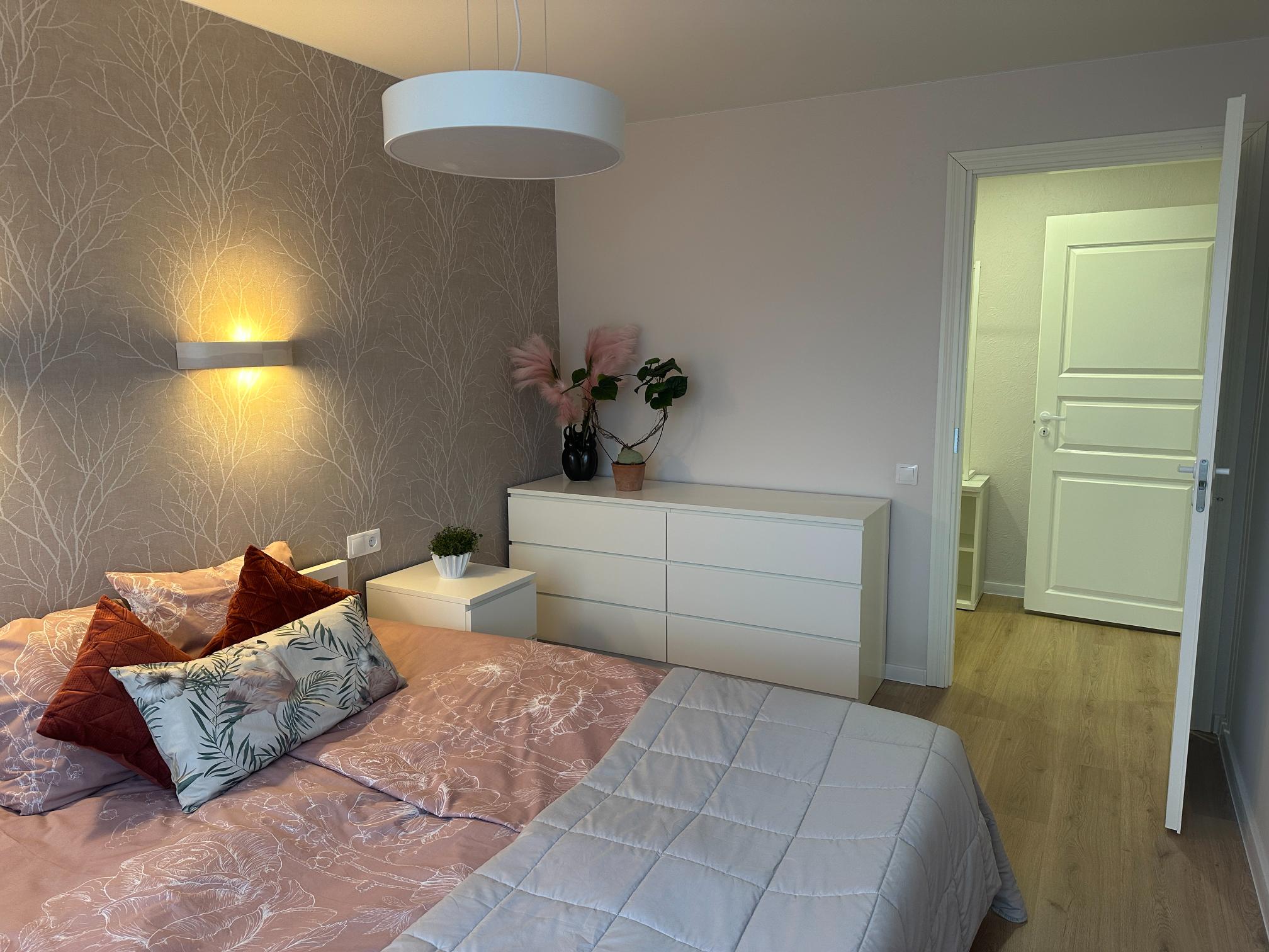 Hubane magamistuba sooja valgustuse, taimede ja disainpatjadega. Minimalistlik valge mööbel.