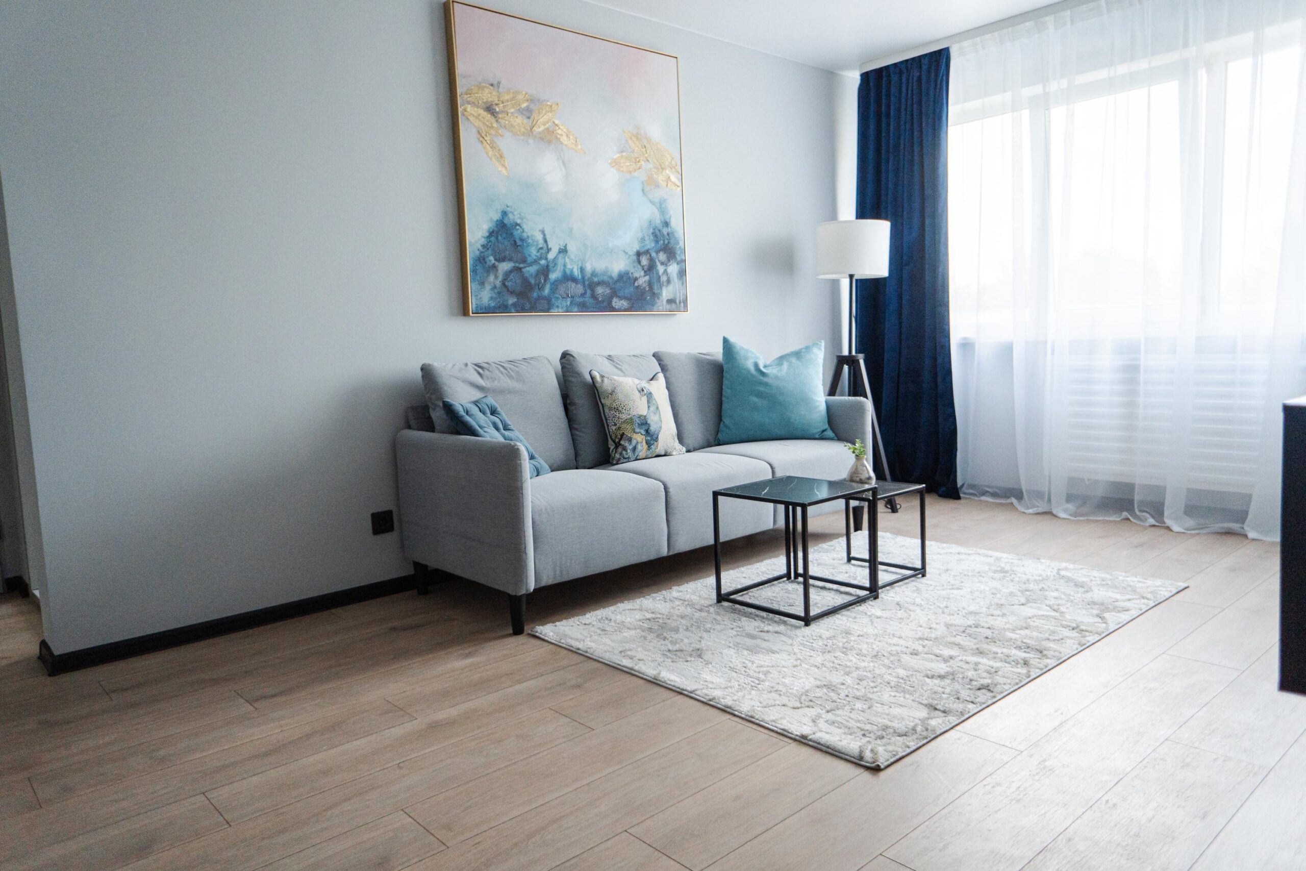 Elegantne ja helge elutuba koos diivani, dekoratiivse kunstiteose ja rahuliku valgustusega.