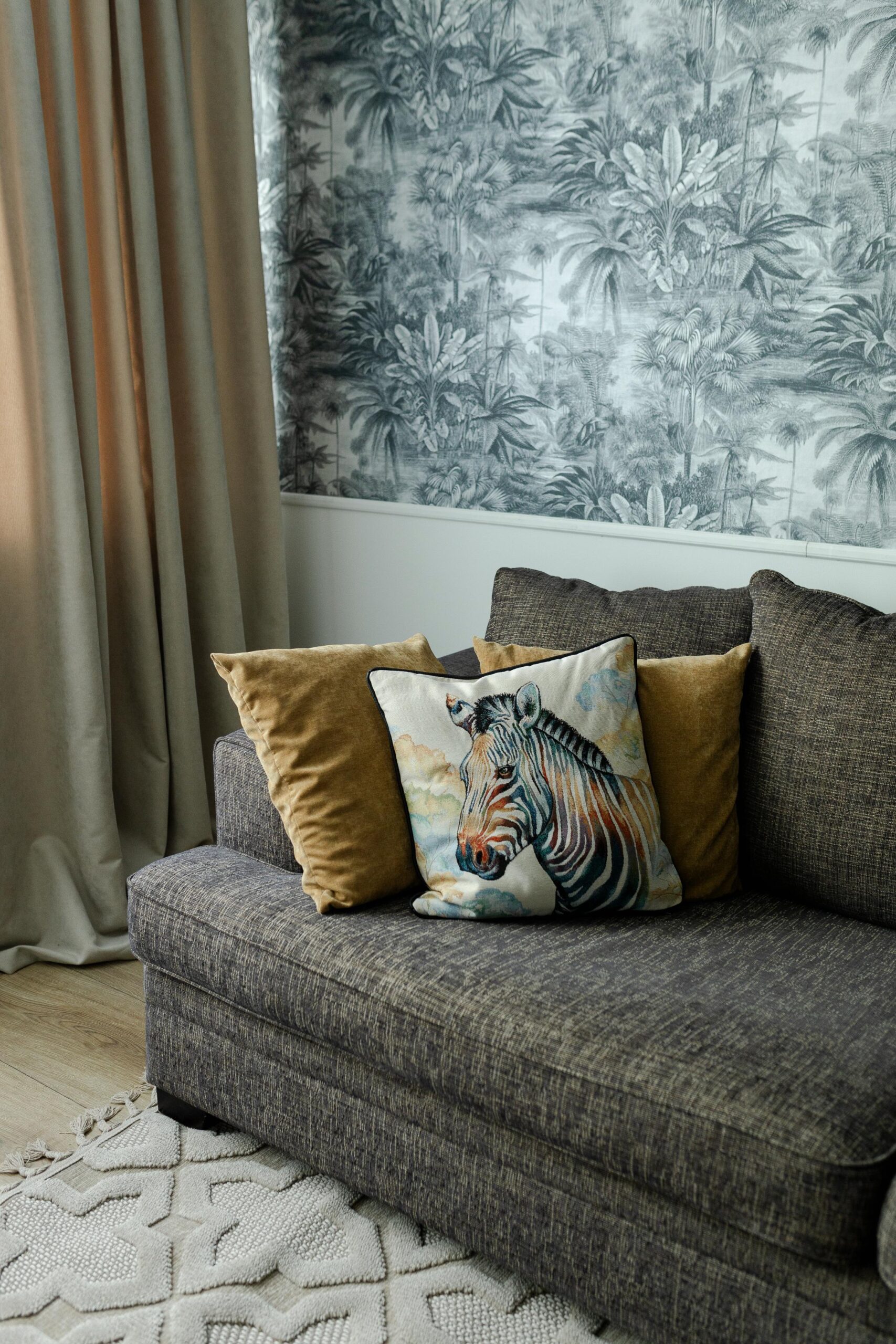 Hubane nurgake halli diivani, troopilise seinatapeedi ja dekoratiivsete patjadega, mis loovad sooja ja koduse õhkkonna.