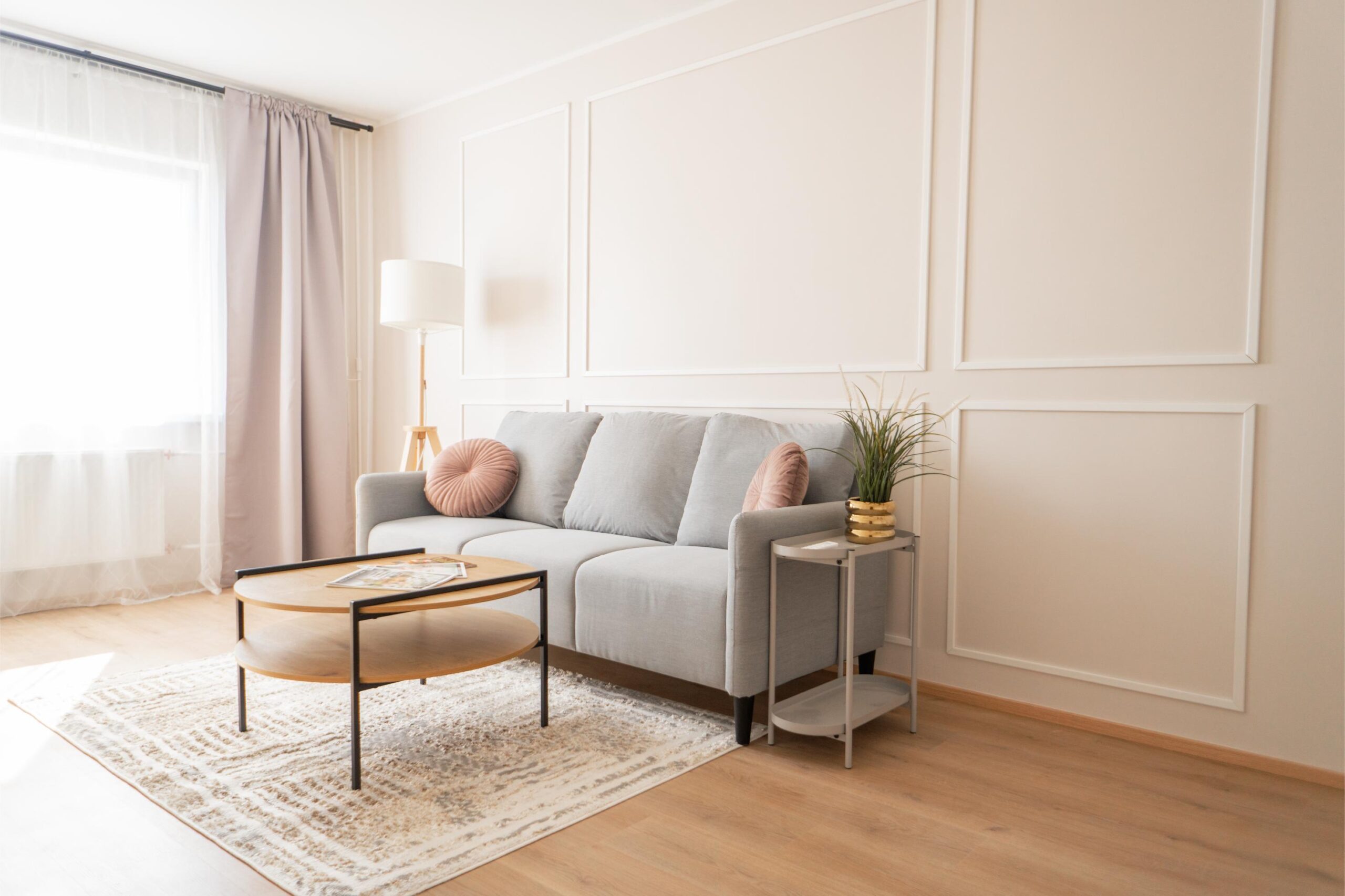 Realtoni kinnisvaraportfelli kuuluv hele ja modernne korter Ida-Virumaal, halli diivani ja klassikaliste seinapaneelidega.